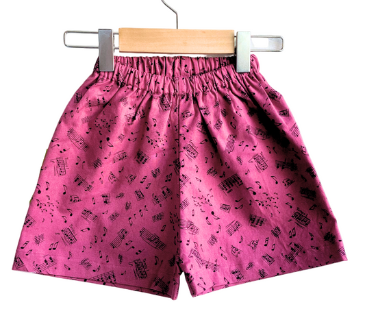 Pink shorts with black pattern on a hanger against a white background