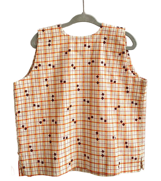 Plaid sleeveless top on a hanger against a textured white background