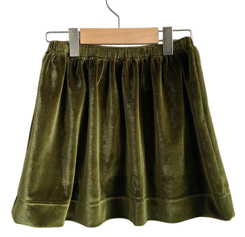 Green velvet skirt on a hanger against a white background