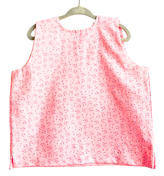 Pink sleeveless top with white floral pattern on a hanger against a white background