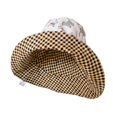 A reversible checkered hat displayed on a stand, with one side featuring a sun and animals design and the other side a plain checkered pattern.