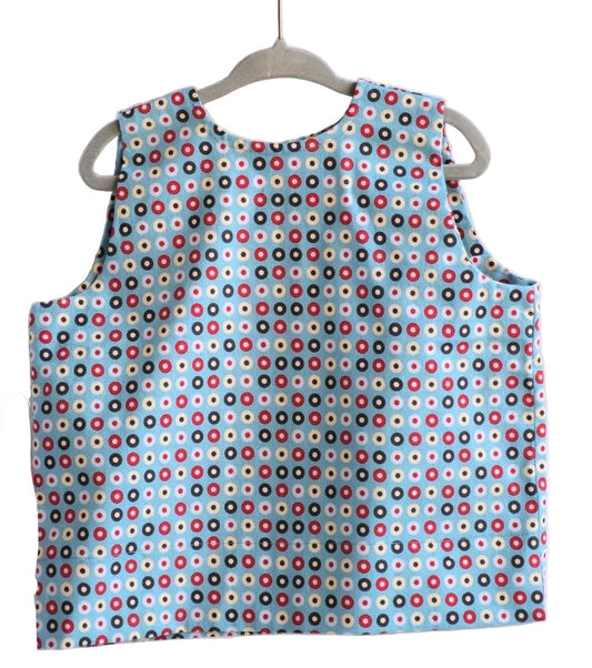 Children's sleeveless shirt with colorful dot pattern on a hanger against a white background