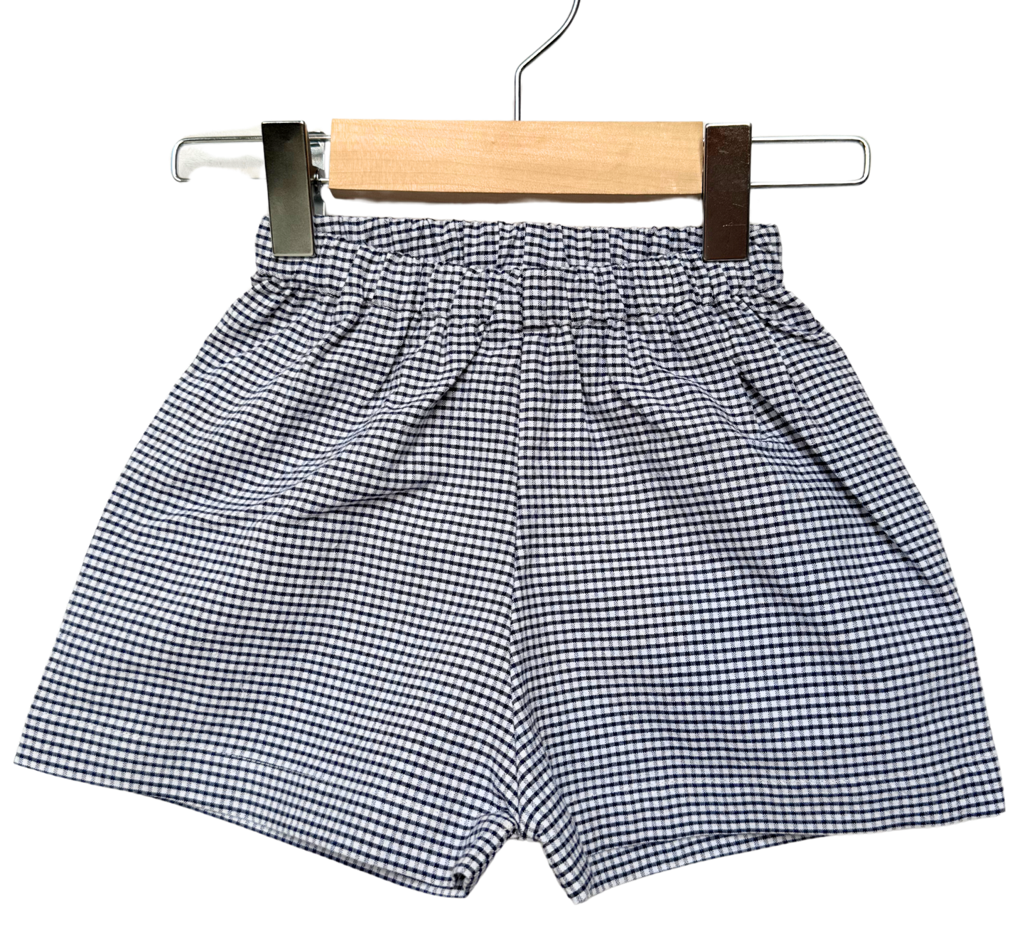 Black and white checkered shorts on a wooden hanger against a white background