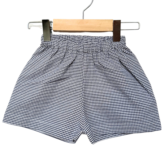 Black and white checkered shorts on a wooden hanger against a white background