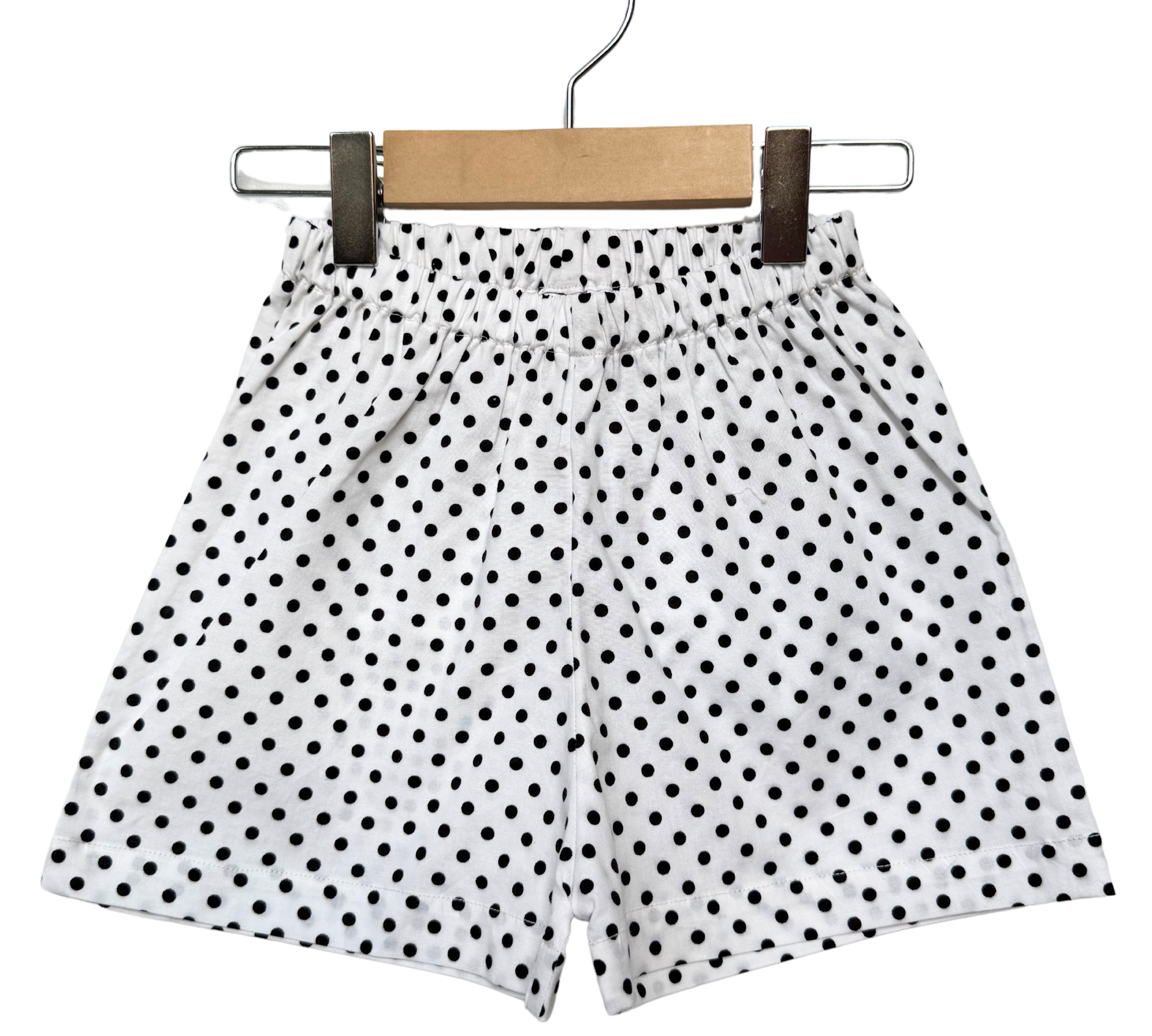Polka dot shorts on a hanger against a white background