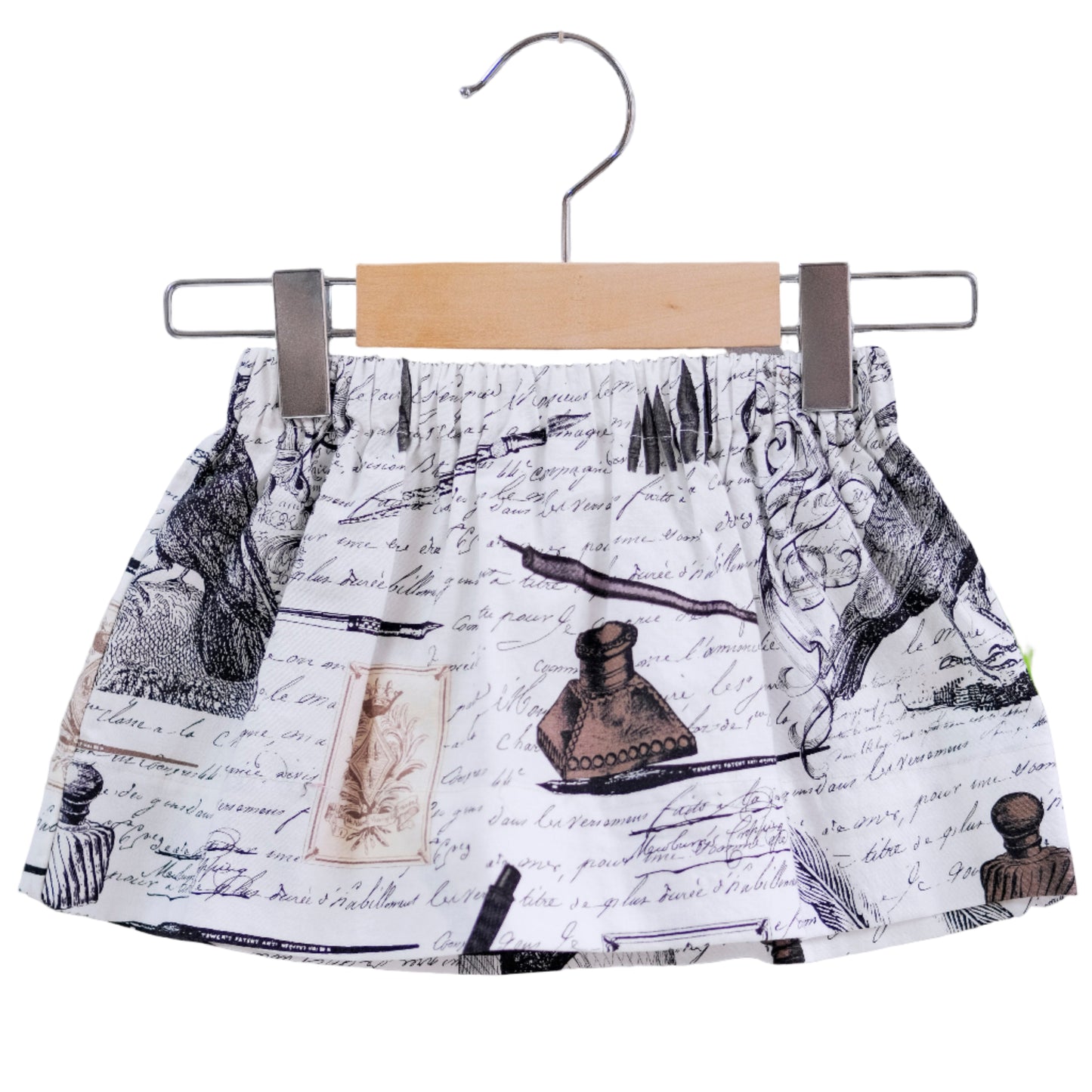 Skirt with vintage inkwell and quill design on a hanger against a white background